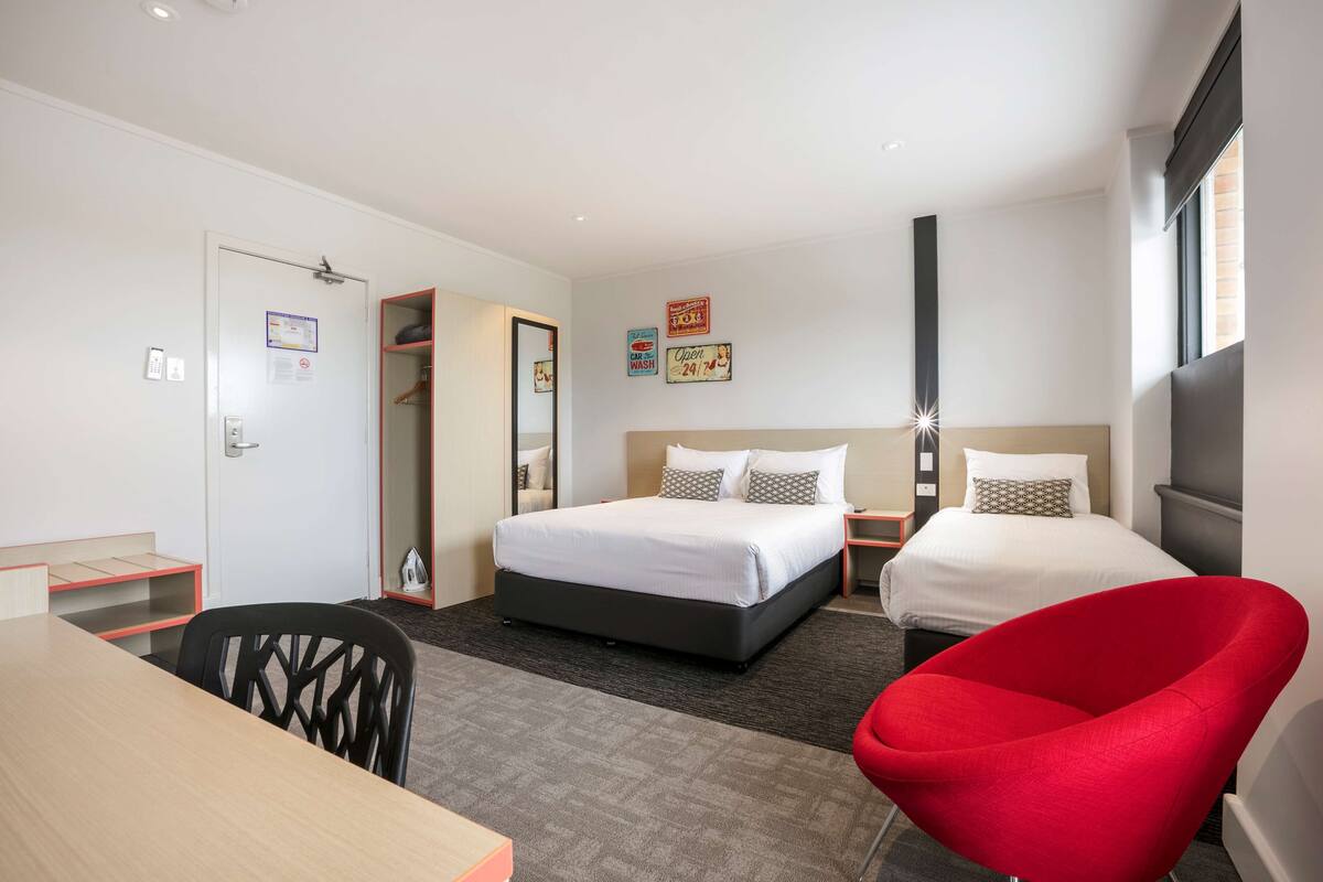 A hotel room with a bed, a desk, a chair, and a wardrobe.