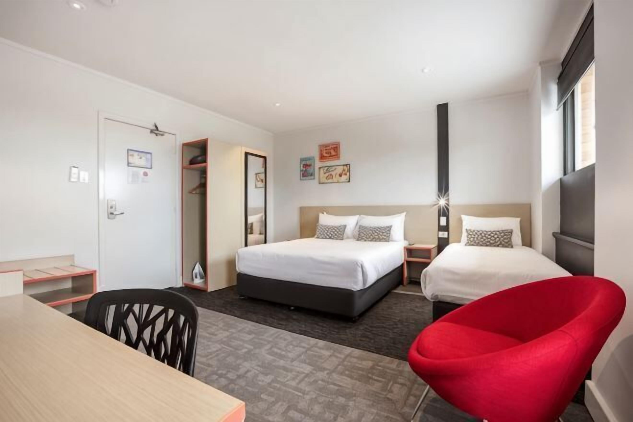 Ein Hotelzimmer mit Bett, Schreibtisch, Stuhl und Kleiderschrank.