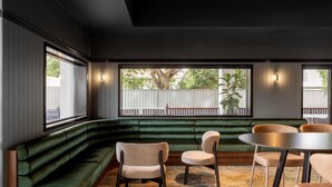 Un interior moderno con un banco tapizado de verde, dos sillas y una mesa redonda.