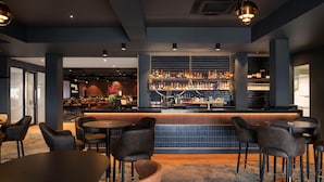 Zona de bar moderna con mostrador, asientos y una amplia selección de licores.