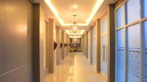 A long, well-lit hallway with a chandelier, large windows, and a seating area at the end. - Khas Pekalongan (Pekalongan)