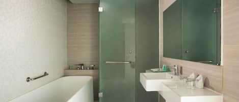 Un baño moderno con una bañera independiente, cabina de ducha con mampara de cristal y tocador con espejo.