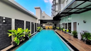 A swimming pool with a view of a restaurant and a building in the background. - Khas Pekalongan (Pekalongan)