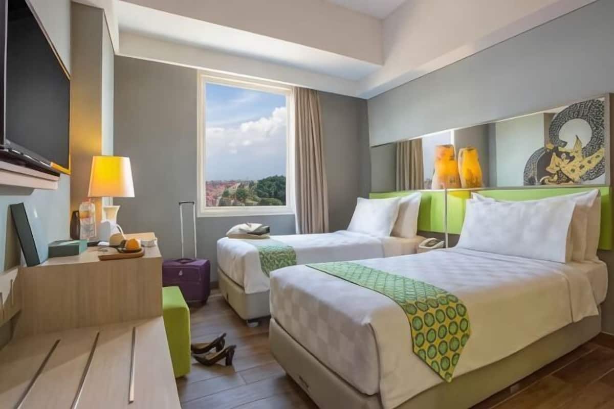 Ett hotellrum med två sängar, ett skrivbord, en TV, ett fönster med utsikt och ett badrum.