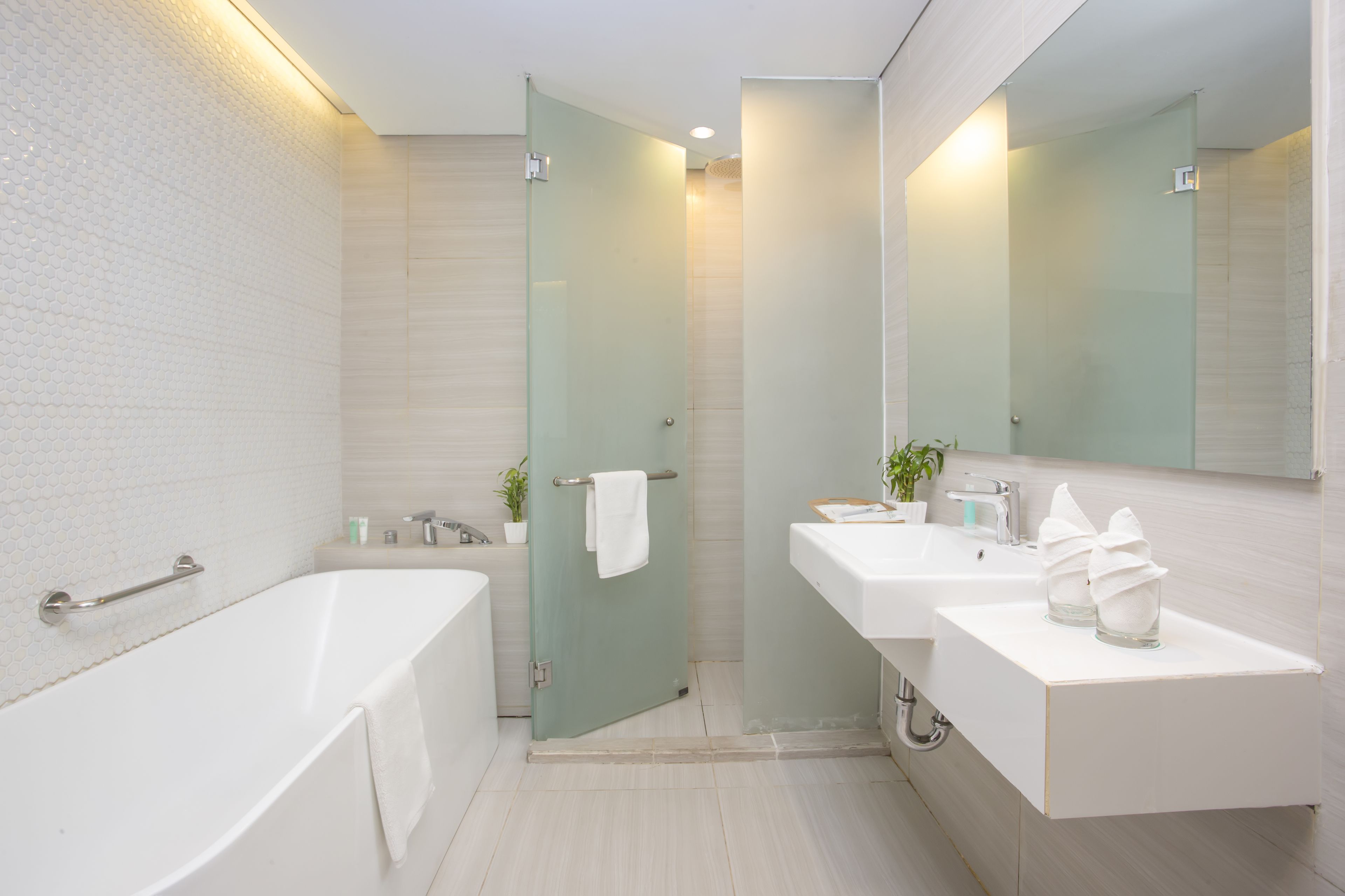A modern bathroom with a bathtub, a glass shower enclosure, and a vanity with a mirror.