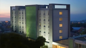 A modern multi-story hotel with a distinctive green facade and illuminated windows. - Khas Pekalongan (Pekalongan)