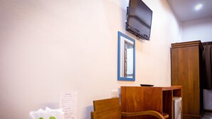 A room with a wooden table, chairs, a TV mounted on the wall, and a wooden wardrobe. - Wangthatum (Si Maha Phot)