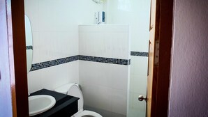 A bathroom with a toilet, sink, and a mirror. - Wangthatum (Si Maha Phot)