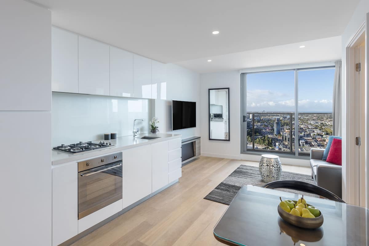 Una cocina moderna con armarios blancos, una estufa a gas y un ventanal con vistas a la ciudad.