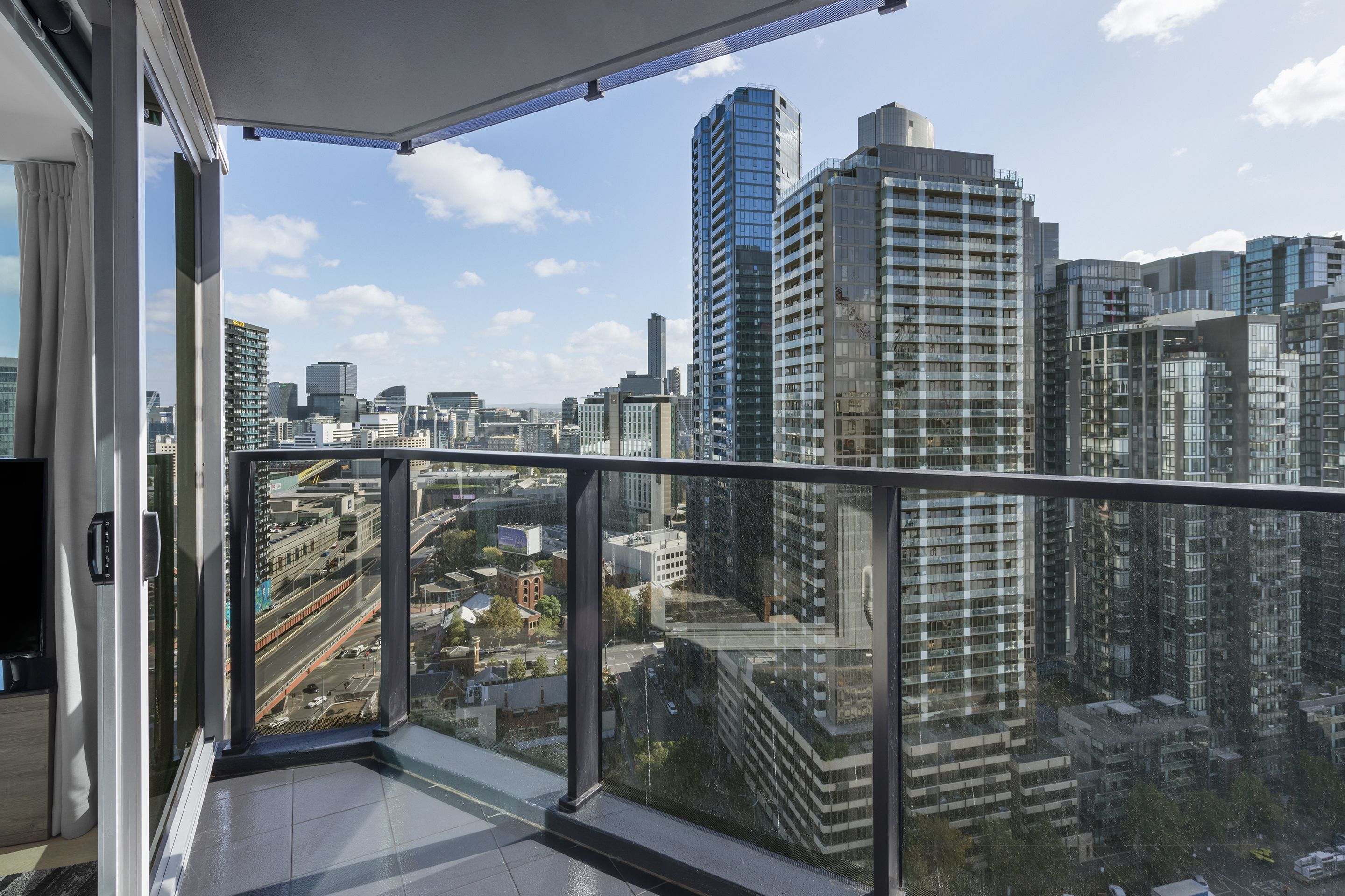 Een hoog gebouw met een glazen balkon met uitzicht over een stadsbeeld.