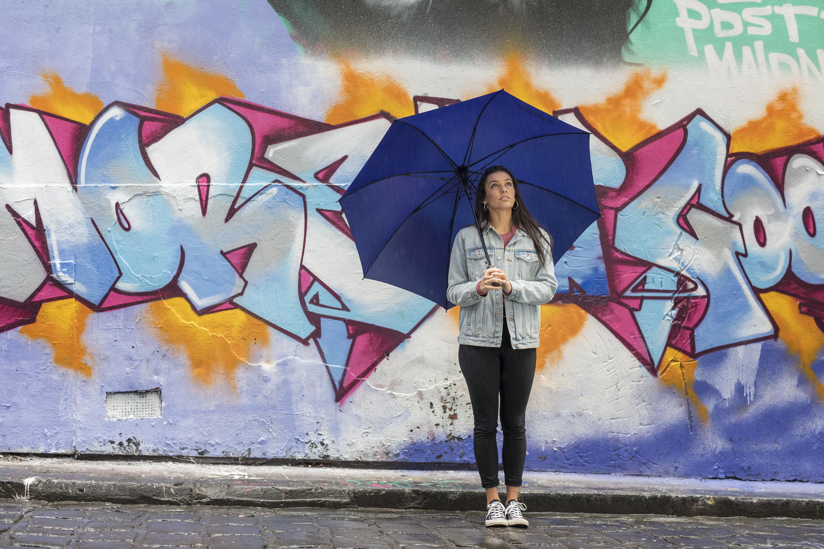 A person standing in front of a colorful graffiti wall.