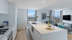 Cuina moderna amb una illa central, forn integrat i una finestra gran que ofereix vista a la ciutat.