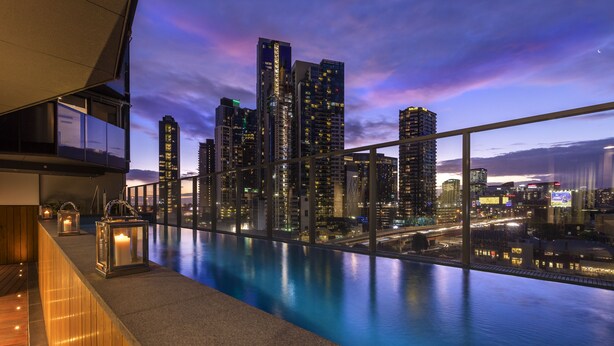 Terrat d'un hotel modern amb piscina que domina un paisatge urbà a la capvespre.