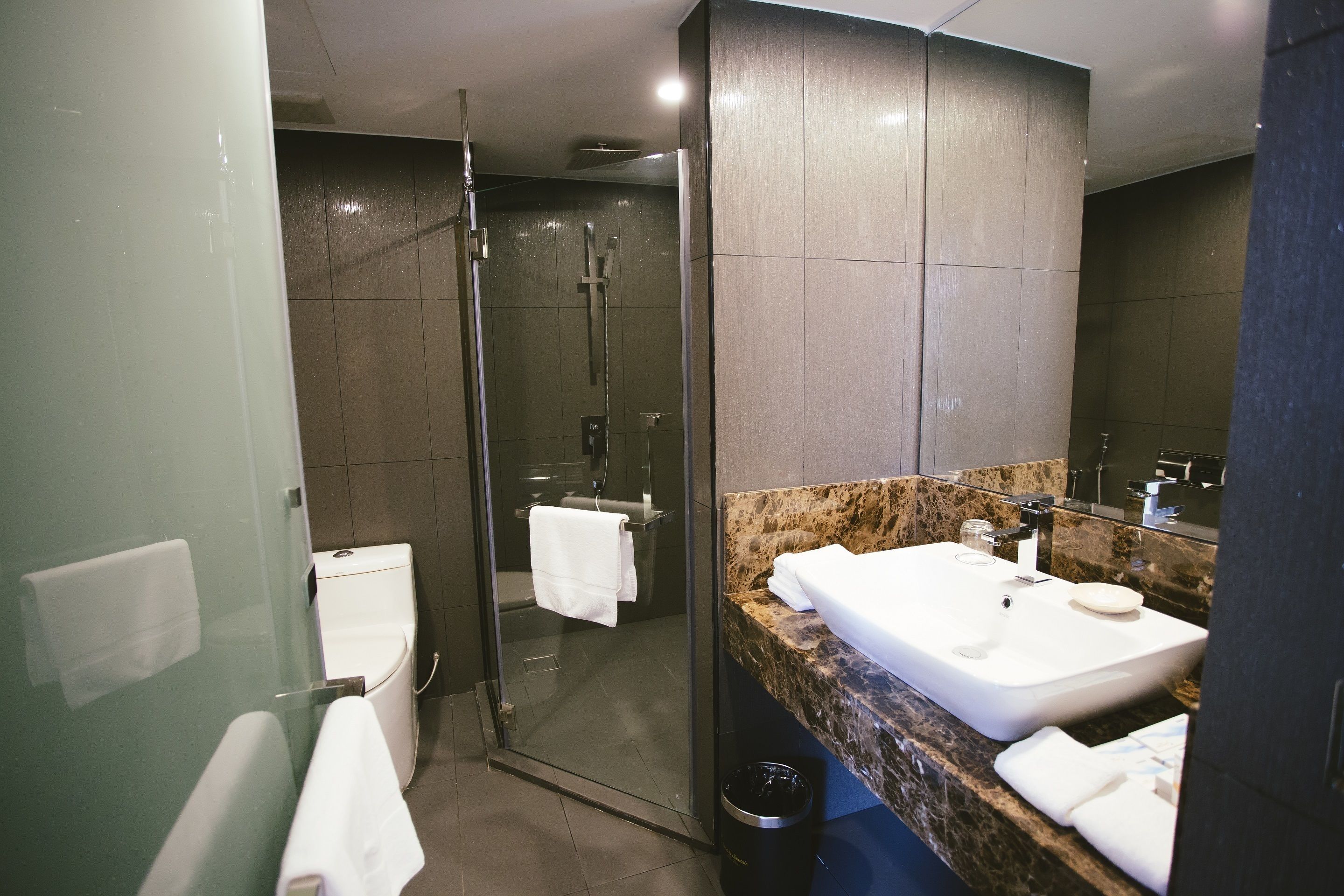 A modern bathroom with a glass-enclosed shower, a white sink, and a marble countertop.