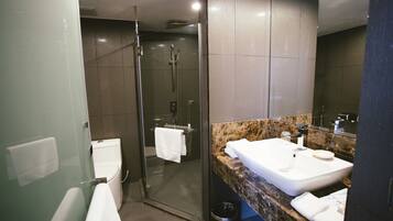 A modern bathroom with a glass-enclosed shower, a white sink, and a marble countertop.