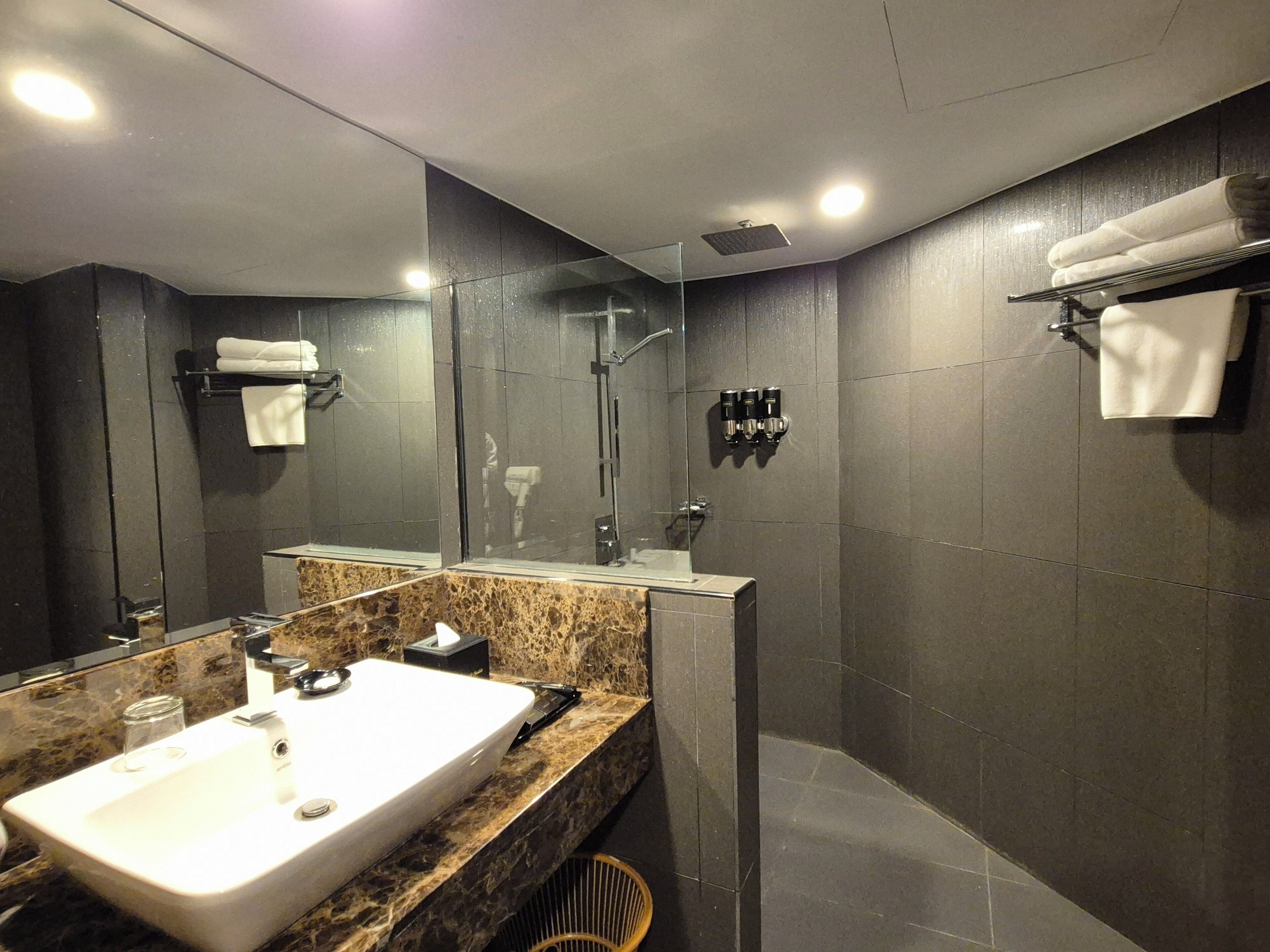 A modern bathroom with a large mirror, a sink, and a shower.
