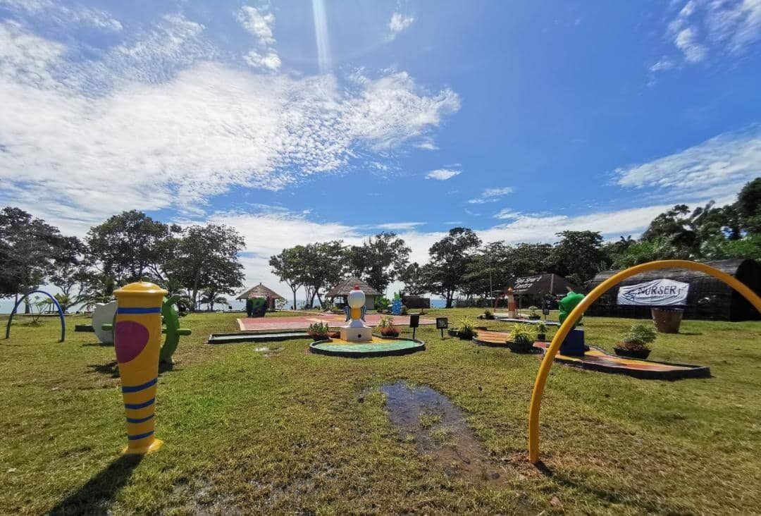 Un parque con juegos infantiles, una fuente y un letrero que dice 'SURFER'.