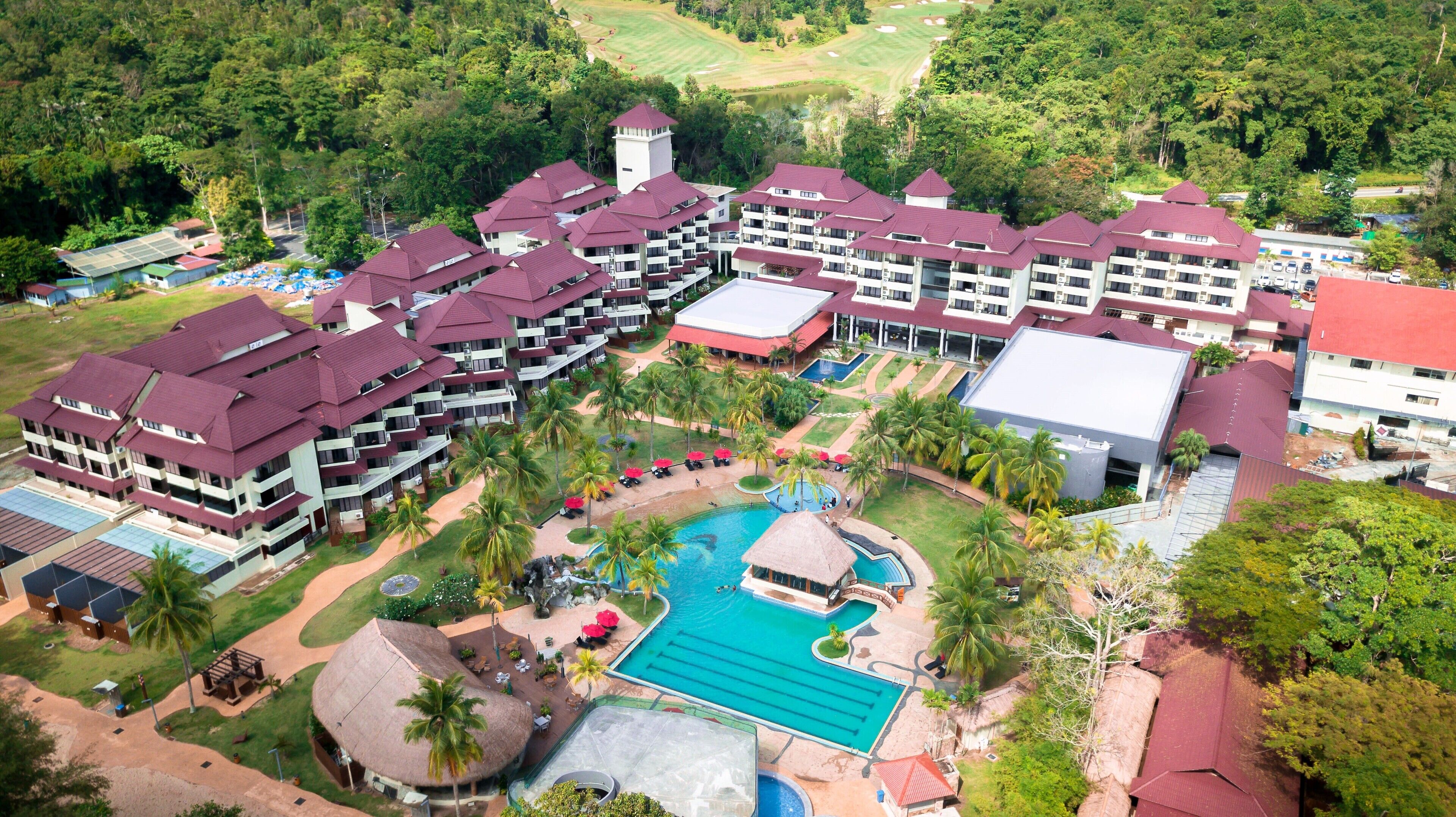 Een resort met meerdere gebouwen, een zwembad en een golfbaan op de achtergrond.
