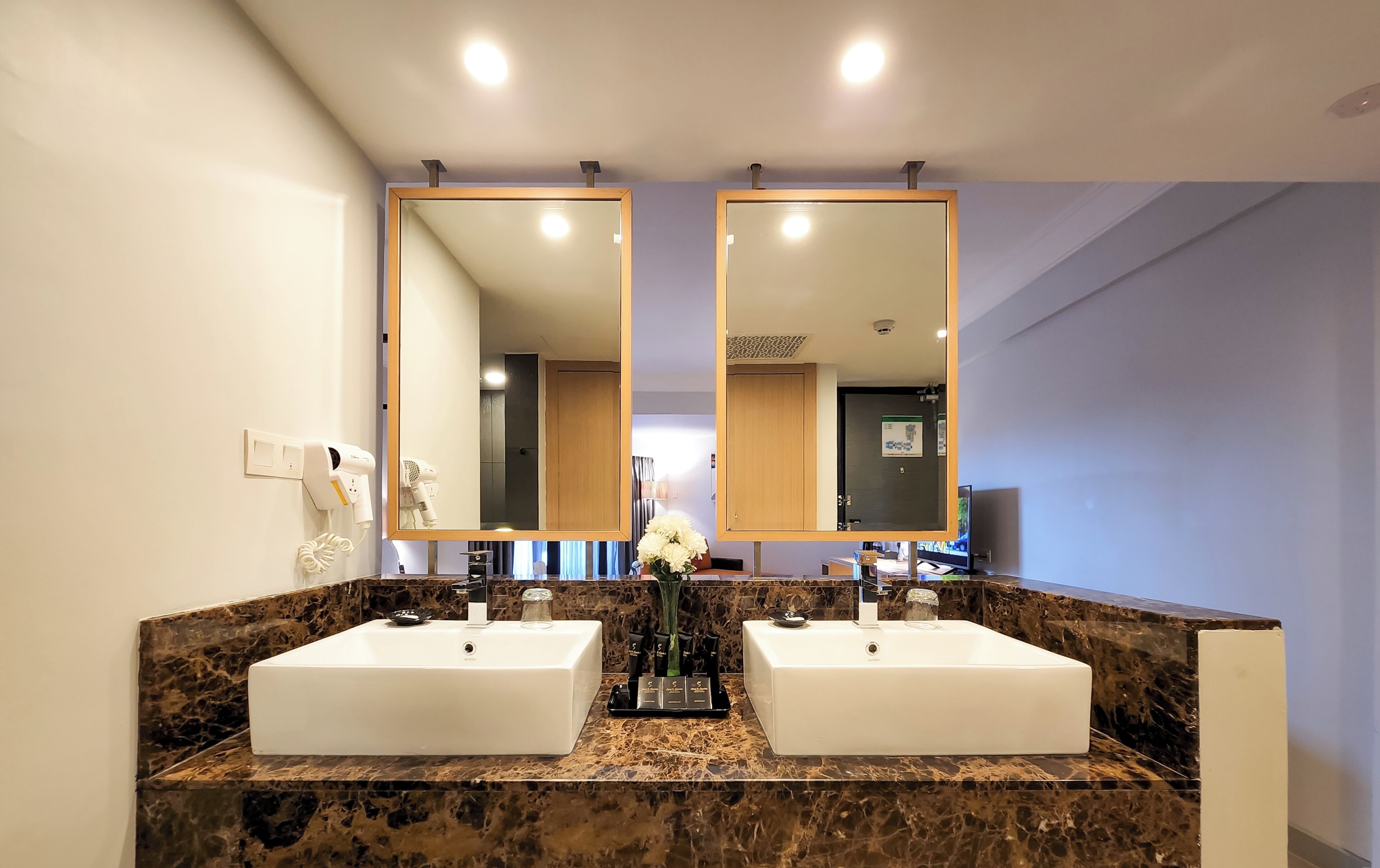 Une salle de bain avec deux lavabos, un grand miroir et un comptoir en marbre.