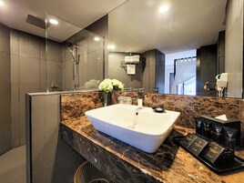 A modern bathroom with a large mirror, a white sink, and a shower area.