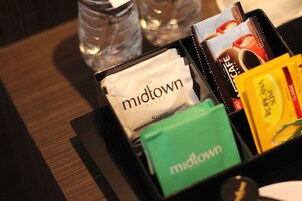 Uma bandeja com vários itens, incluindo uma sacola de hotel 'midtown', um produto da marca 'Sugar' e um produto da marca 'KONKA'.