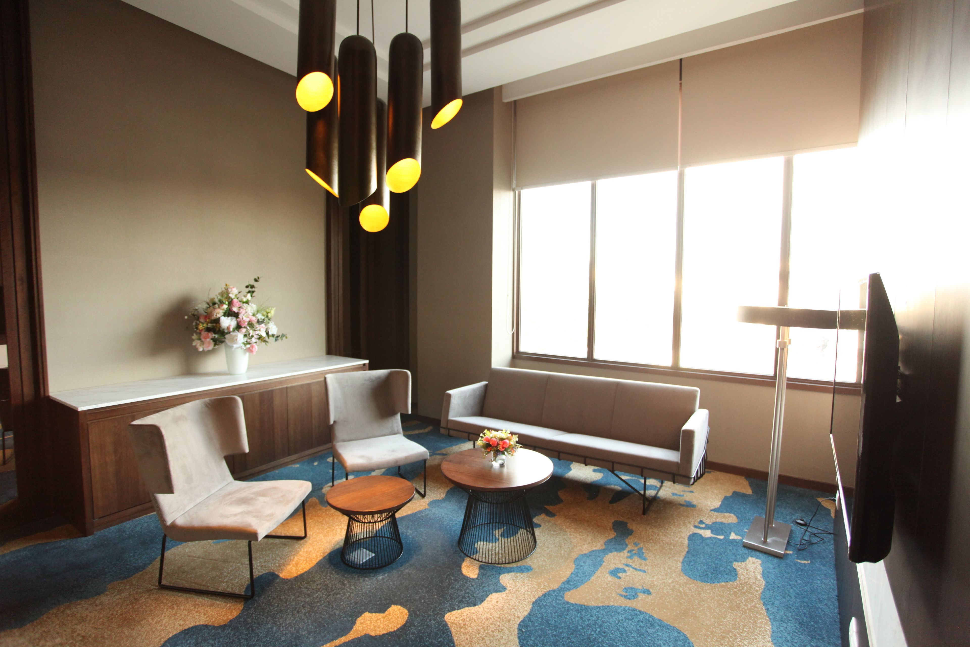 A modern lounge area with a sofa, chairs, a coffee table, and a TV.