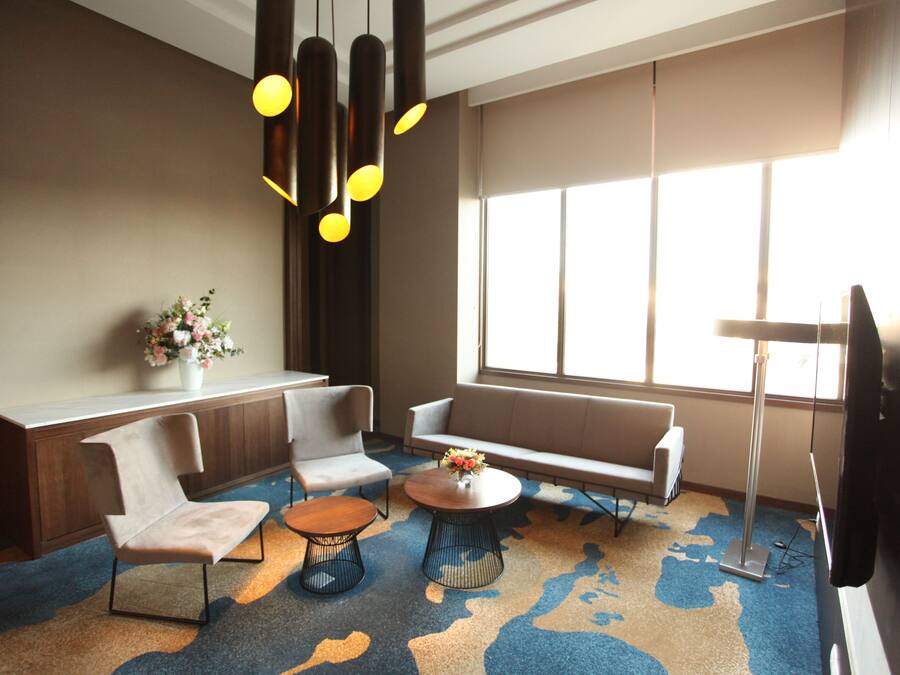 A modern lounge area with a sofa, chairs, a coffee table, and a TV.