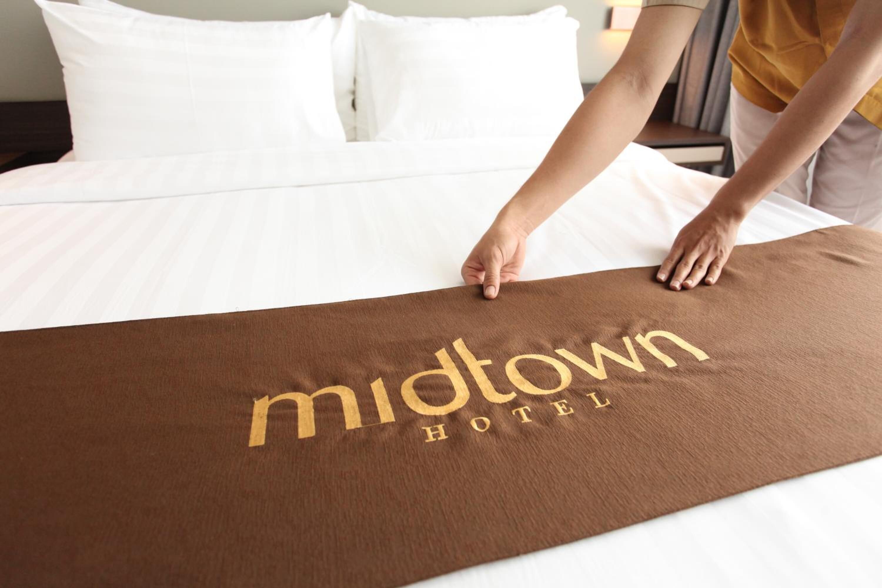 A bed with a brown cover displaying the text "midtown hotel".