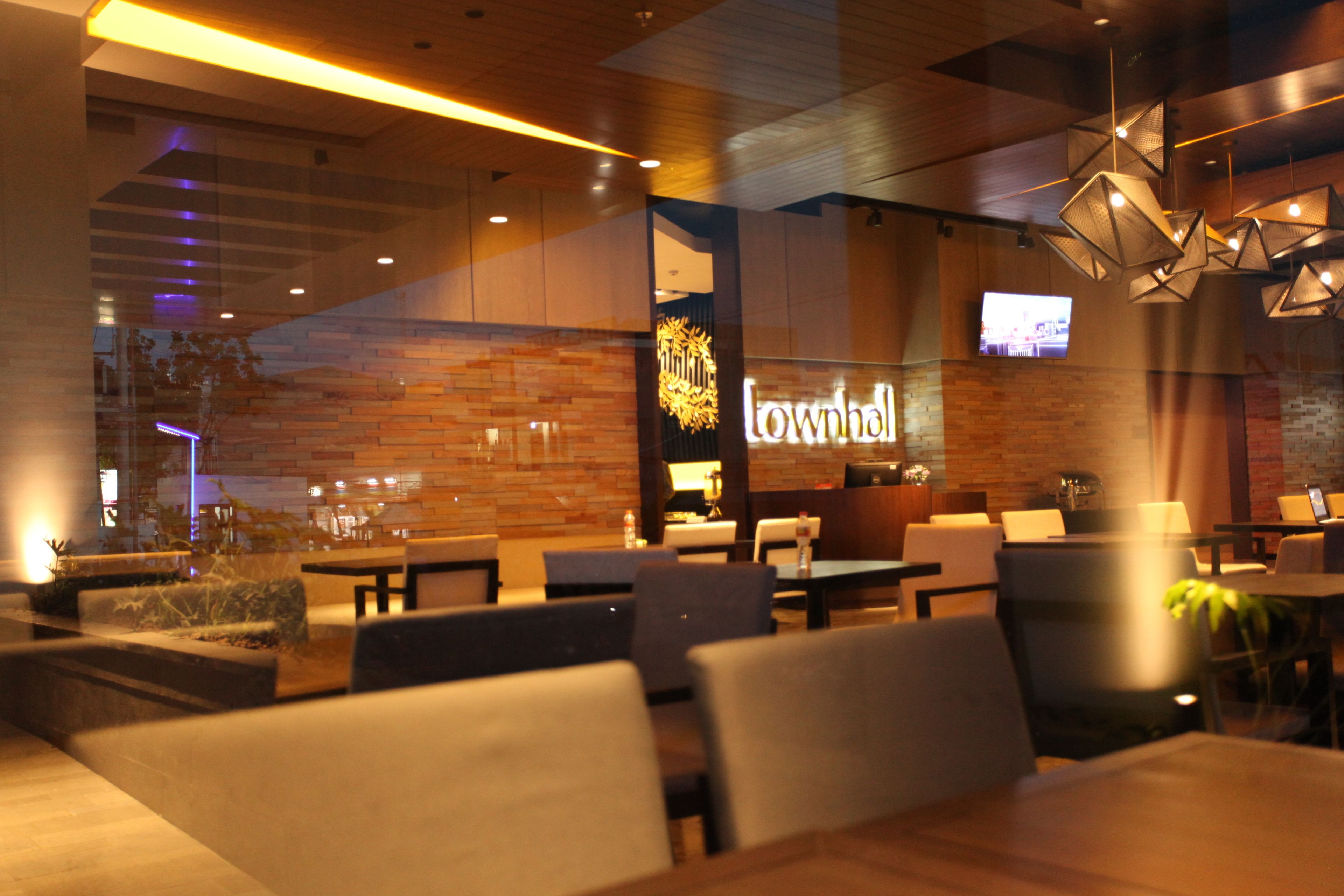L’intérieur d’un restaurant avec des murs en bois, un éclairage moderne et un écran de télévision bien visible.