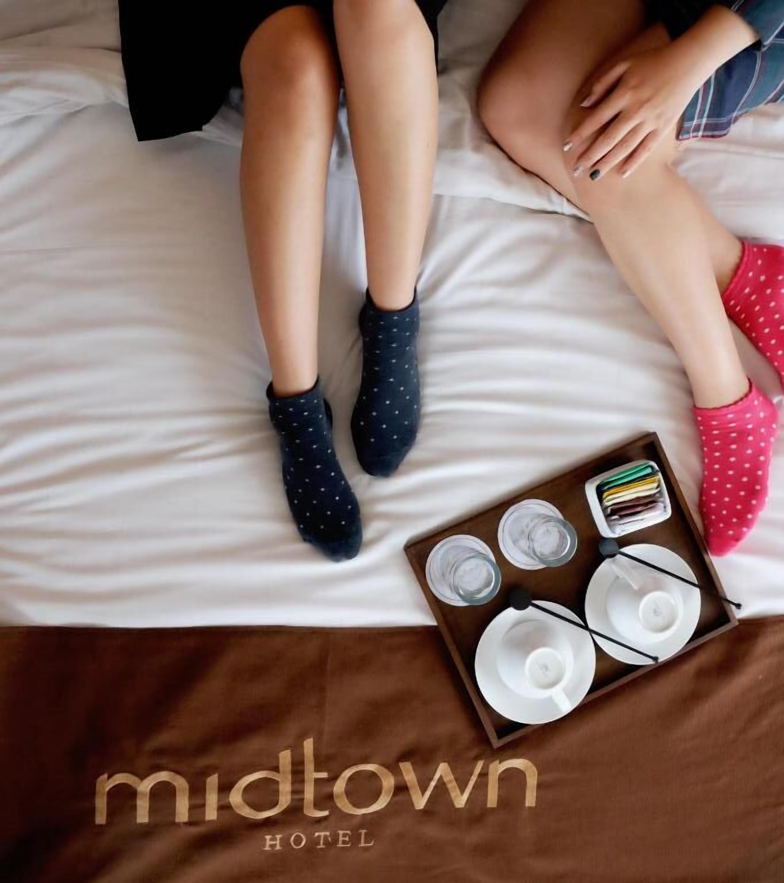 Un lit avec un plateau contenant divers éléments pour le petit-déjeuner, notamment des assiettes, des tasses et des verres, ainsi qu’une paire de chaussettes.