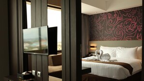 Ein Hotelzimmer mit Bett, Fernseher, Schreibtisch und Blick ins Freie.