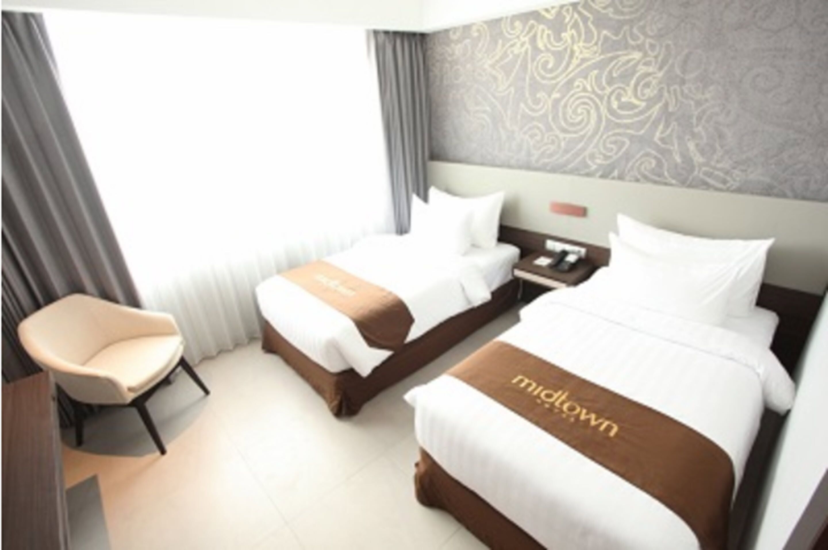 A hotel room with two beds, a chair, and a nightstand.