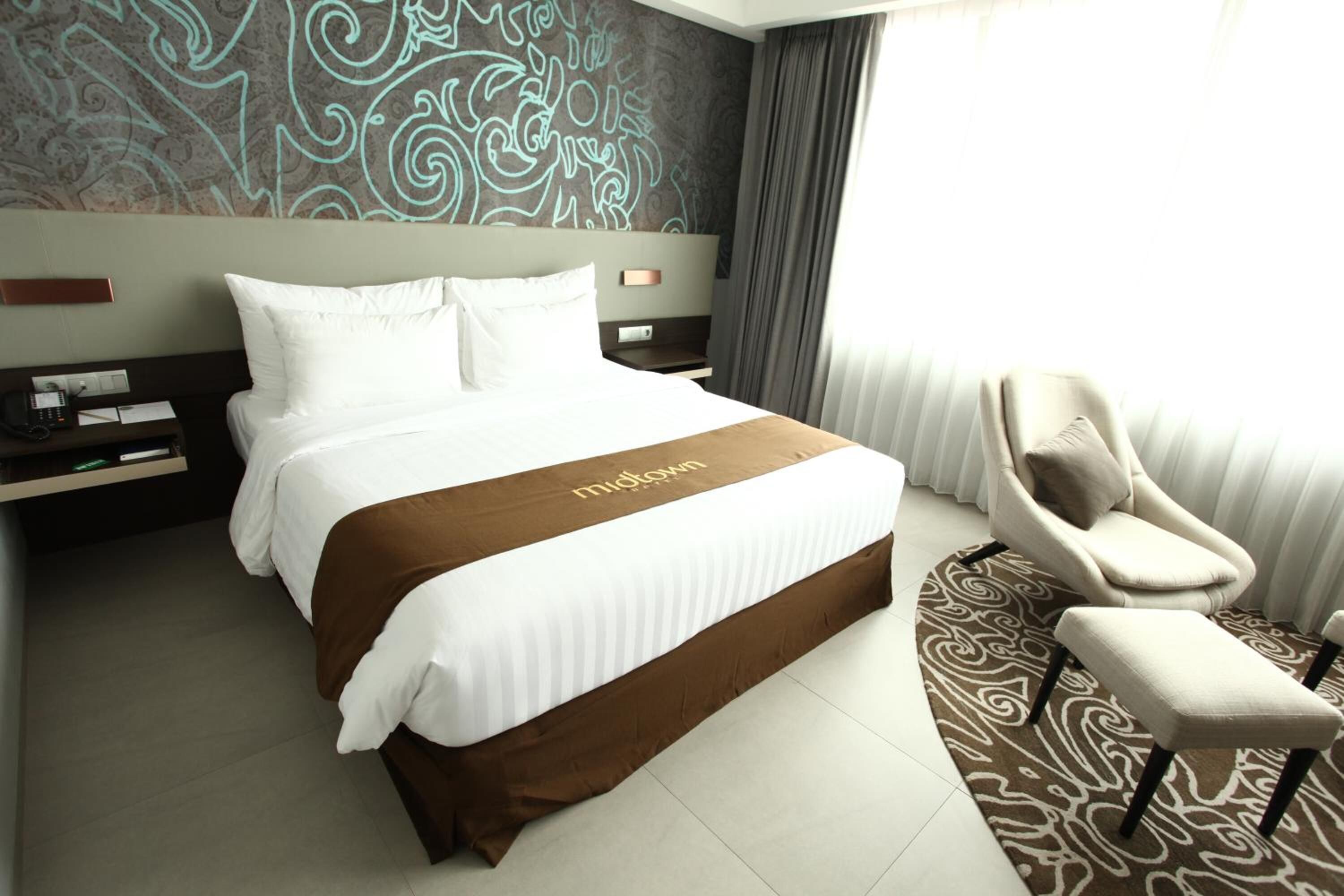 A hotel room with a large bed, a chair, and a patterned wall.