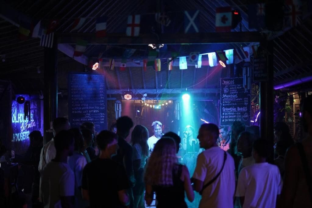 A crowded bar or club with a stage and a menu board.