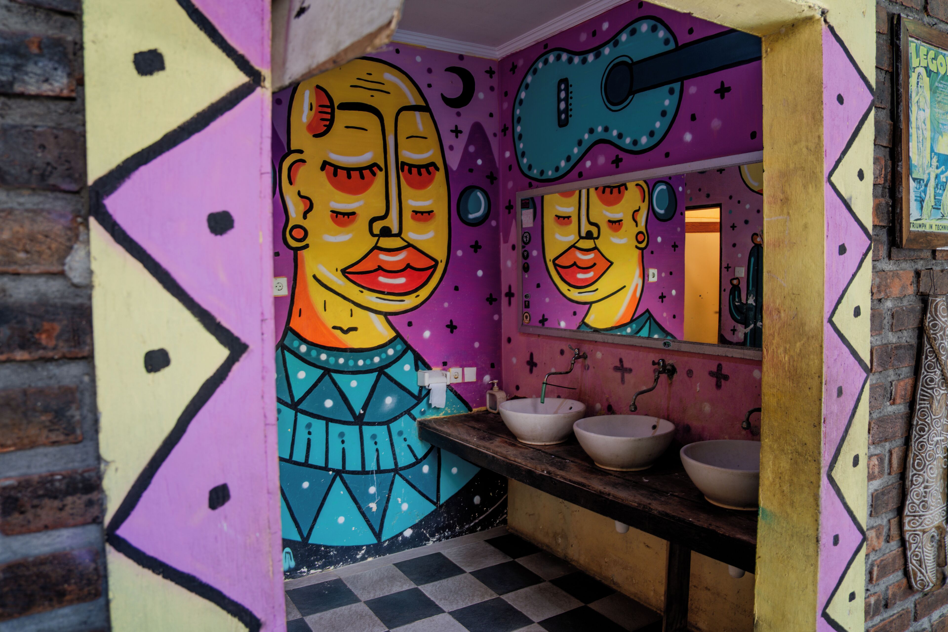 Ein Badezimmer mit Schachbrettboden, einem Waschbecken und einem Spiegel.