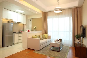 Una sala moderna con sofá, una mesa de centro y una zona de cocina con refrigerador y armarios.