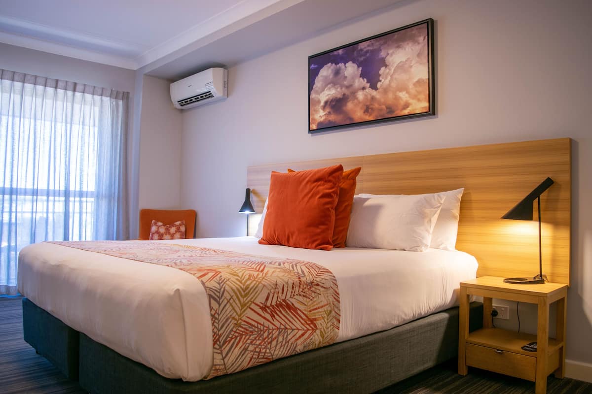 Une chambre d’hôtel avec un lit, une table de chevet, une lampe et un tableau au mur.