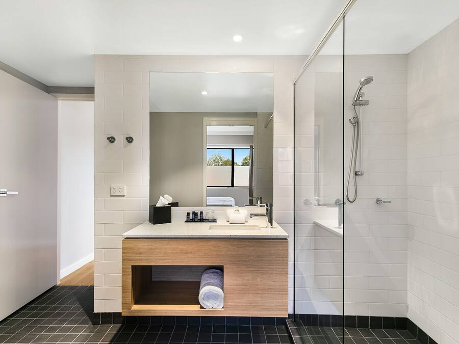 Un baño moderno con tocador de madera, cabina de ducha de vidrio y un espejo grande.