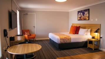Ein Hotelzimmer mit Bett, Schreibtisch, Stuhl, Tisch und einem Bild an der Wand.