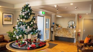 Een receptiehal met een kerstboom, een receptiebalie en lederen zitplaatsen.