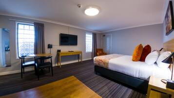 A hotel room with a bed, a desk, a chair, a TV, and a window.