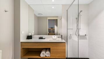 A modern bathroom with a wooden vanity, a glass shower enclosure, and a mirror above the sink.