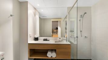 A modern bathroom with a glass shower enclosure, a wooden vanity, and a built-in shelf with towels.