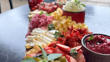 A charcuterie board with various meats, cheeses, and pickles on a table outside a restaurant.