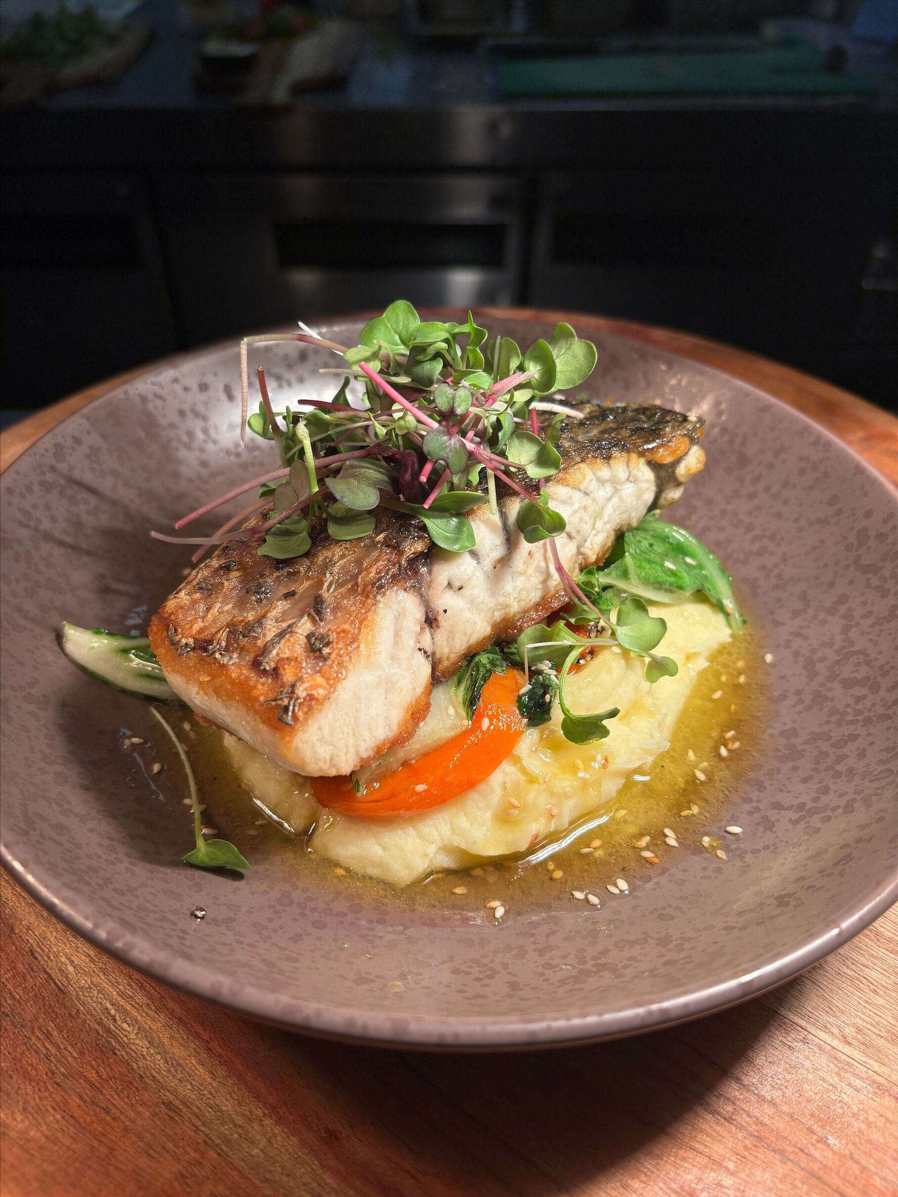 Une assiette contenant un filet de poisson, des légumes et une sauce.