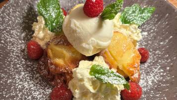 A dessert plate with a scoop of ice cream, raspberries, and mint leaves.