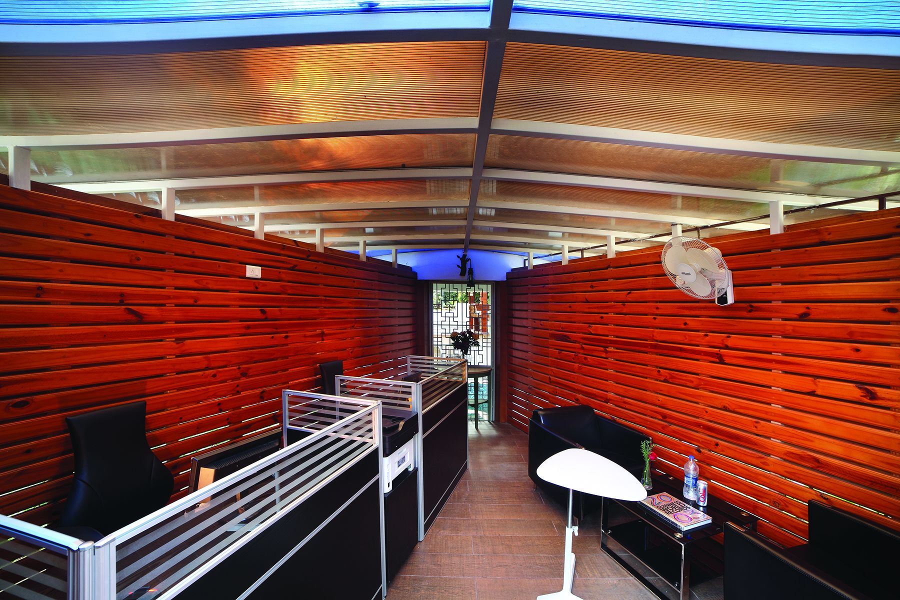 A modern interior with wooden panel walls, a central walkway, and a ceiling with a blue light fixture.