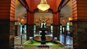 A lobby with a central fountain, stone walls, and a chandelier. - Wetzlar Resorts and Hotels (Muvattupuzha)