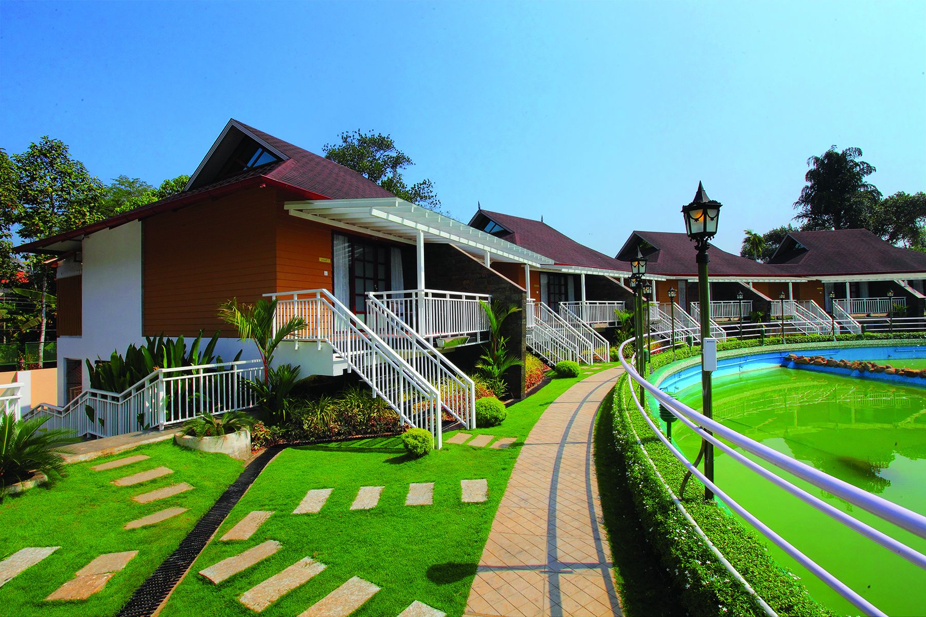 A hotel with a swimming pool, a covered walkway, and a well-maintained lawn.