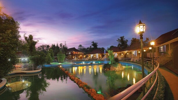 A resort with a swimming pool, a bridge, and a building with a red roof. - Wetzlar Resorts and Hotels (Muvattupuzha)